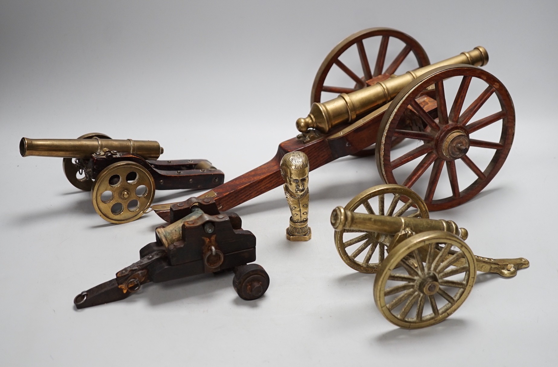 A bronze 'Napoleon bust' desk seal, 8.5cm tall, together with four models of cannons. Largest 39cm wide